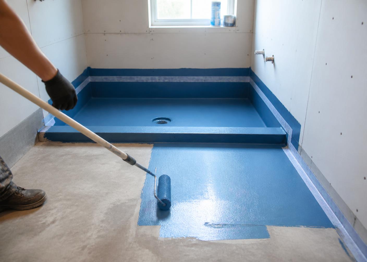 Liquid waterproofing membrane applied to a bathroom floor, shower hob and wall junctions